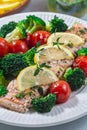 Baked salmon fillet with broccoli and tomato, salmon steak with vegetables, vertical, closeup Royalty Free Stock Photo