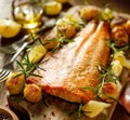 Baked salmon fillet with hasselback potatoes, lemon and fresh rosemary served on a wooden board Royalty Free Stock Photo