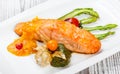 Baked salmon garnished with physalis, asparagus, tomatoes with herbs on wooden background. Royalty Free Stock Photo