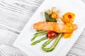 Baked salmon garnished with physalis, asparagus, tomatoes with herbs on wooden background. Royalty Free Stock Photo