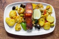 Baked salmon meat with potatoes and vegetables on a white plate in a restaurant