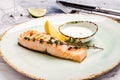 Baked Salmon Steak with herbs, sauce and lemon slice on plate. Delicious fried fish served coarse salt and cherry tomato branch Royalty Free Stock Photo