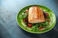 Baked salmon steak with tomato, onion, mix of green leaves salad in a plate. healthy food Royalty Free Stock Photo