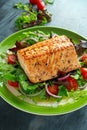 Baked salmon steak with tomato, onion, mix of green leaves salad in a plate. healthy food Royalty Free Stock Photo