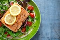 Baked salmon steak with tomato, onion, mix of green leaves salad in a plate. healthy food Royalty Free Stock Photo