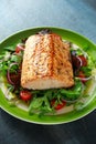 Baked salmon steak with tomato, onion, mix of green leaves salad in a plate. healthy food Royalty Free Stock Photo