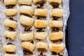 Baked sausage rolls on black table - Top view photo of puff pastry snacks in foil lined tin