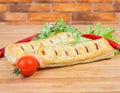 Baked sausage rolls with herbs and vegetables close-up