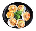 Baked Scallops with Cheese and green Parsley black ceramic dish isolated on white background with clipping path. Grill seashell Royalty Free Stock Photo