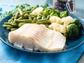 Baked sea fish cod fillet with vegetables on blue plate, blue na Royalty Free Stock Photo