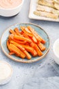 Baked season carrot sticks with sauce and hummus