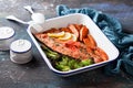 Baked sockeye salmon fish fillet with roasted sweet potato and broccoli, in enameled baking dish