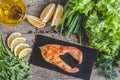 Baked steak trout fish on a stone board, around greens, leaves,