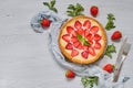 Baked strawberry cheesecake on the gray background with copy space decorated with many fresh strawberries, mint leaves, gray cloth