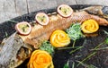 Baked sturgeon fish with rosemary, lemon and passion fruit on plate on wooden background close up.