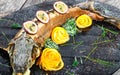 Baked sturgeon fish with rosemary, lemon and passion fruit on plate on wooden background close up