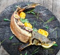 Baked sturgeon fish with rosemary, lemon and passion fruit on plate on wooden background close up. Royalty Free Stock Photo