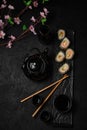 Baked sushi roll, chopsticks, sake bottle, cups and black teapot Royalty Free Stock Photo