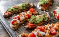 Baked sweet potato toast with roasted chickpeas, tomatoes, goat cheese, sauce guacamole, avocado, seedlings on baking tray