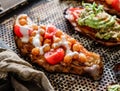 Baked sweet potato toast with roasted chickpeas, tomatoes, goat cheese, sauce guacamole, avocado, seedlings on baking tray over