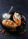 Baked sweet potato or yam, stuffed with chickpeas, rice, vegetables, red chilli pepper and yogurt sauce dressing. Overhead view, Royalty Free Stock Photo