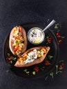 Baked sweet potato or yam, stuffed with chickpeas, rice, vegetables, red chilli pepper and yogurt sauce dressing. Top view, dark Royalty Free Stock Photo