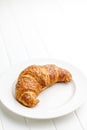Baked tasty croissant on plate on white table Royalty Free Stock Photo