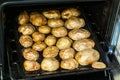 Baked unpeeled potatoes on a baking tray, cooked vegetables