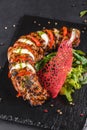 Baked Veal with mozzarella cheese, tomatoes, pesto sauce and green salad on black sbackground. Hot Meat Dishes Royalty Free Stock Photo