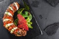 Baked Veal with mozzarella cheese, tomatoes, pesto sauce and green salad on black sbackground. Hot Meat Dishes. Top view, flat lay Royalty Free Stock Photo