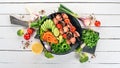 Baked veal shish kebab on a plate with fresh vegetables. On a wooden background. Top view.