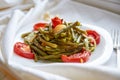 Baked vegetables with silver fork on a white plate cooked in the oven - bean, potato, onion, tomato. On a white surface close up