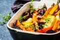 Baked vegetables with thyme in the oven dish, blue background