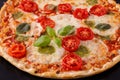 Baked vegetarian crusty pizza with mozzarella, cherry tomatoes, pesto sauce and basil leaves closeup Royalty Free Stock Photo