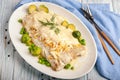 Baked white fish fillet in a thick sauce with vegetable side dish