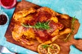 Baked whole chicken with sauces on wooden board on blue background.