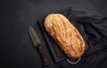 Baked whole oval bread made from white wheat flour on a black table, top view Royalty Free Stock Photo