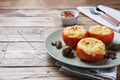 Baked whole tomatoes stuffed with mushrooms and cheese with seasonings on a wooden background. Copy space