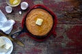 Yellow Cornbread in cast iron skillet on rustic wood table top view with ingredients Royalty Free Stock Photo