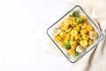 Baked yellow carrot with broccoli and cauliflowers in glass dish on white wooden table, flat lay. Space for text