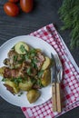 Baked young potatoes with meat and vegetables. Dark wooden background Royalty Free Stock Photo