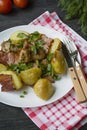 Baked young potatoes with meat and vegetables. Dark wooden background Royalty Free Stock Photo