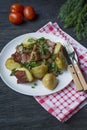 Baked young potatoes with meat and vegetables. Dark wooden background Royalty Free Stock Photo