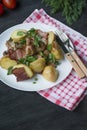 Baked young potatoes with meat and vegetables. Dark wooden background Royalty Free Stock Photo