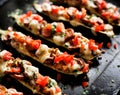 Baked zucchini boats stuffed with vegetarian sausages, tomatoes and cheese, seasoned with herbs on a black background Royalty Free Stock Photo