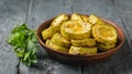 Baked zucchini slices in a clay bowl on a black wooden table. Vegetarian dish. Natural plant food