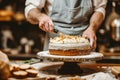 Baker adding frosting to layered cake. Baking a cake at home