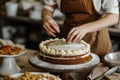 Baker adding frosting to layered cake. Baking a cake at home