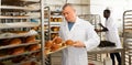 Baker arranging trays with bakery products on trolley Royalty Free Stock Photo