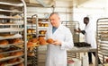 Baker arranging trays with bakery products on trolley Royalty Free Stock Photo